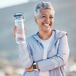 Woman smiling with water bottle on hike outside