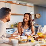 Couple smiling while enjoying meal together at home