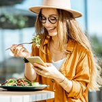 Woman smiling while looking at her phone and eating