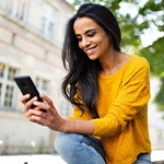 Woman smiling while looking at phone outside