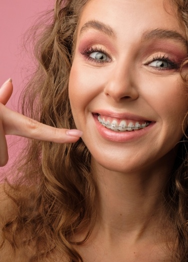 Smiling woman pointing to her clear and ceramic braces