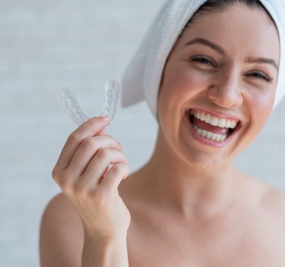 Smiling woman holding a sleep apnea treatment appliance