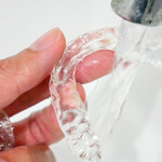 a person rinsing off their invisalign aligners