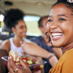 a woman smiling while enjoying a burger