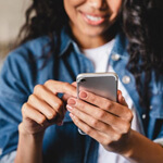 a woman smiling and using her cell phone