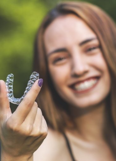 Smiling woman holding an Invislaign tray