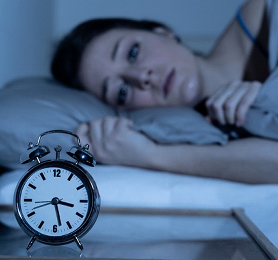 Woman with sleep apnea in Palm Harbor, FL lying awake and looking at clock