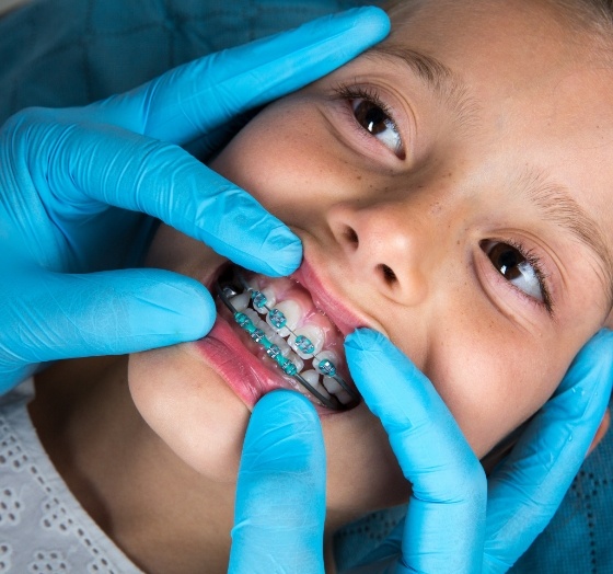 Orthodontist examining child's smile during traditional braces treatment