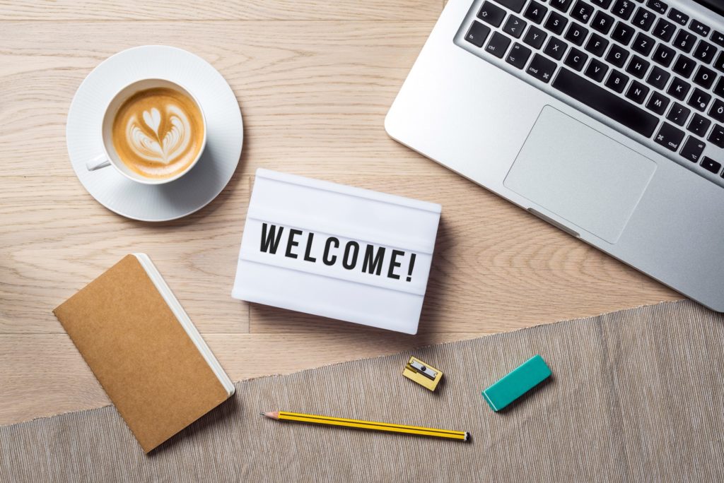 Welcome sign lying on desk next to office supplies