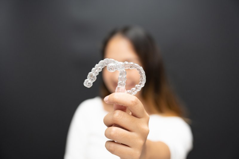 young woman holding up clear aligners