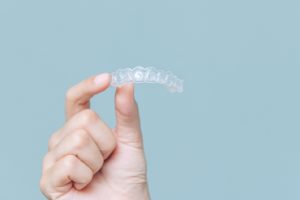 a closeup of a patient holding Invisalign