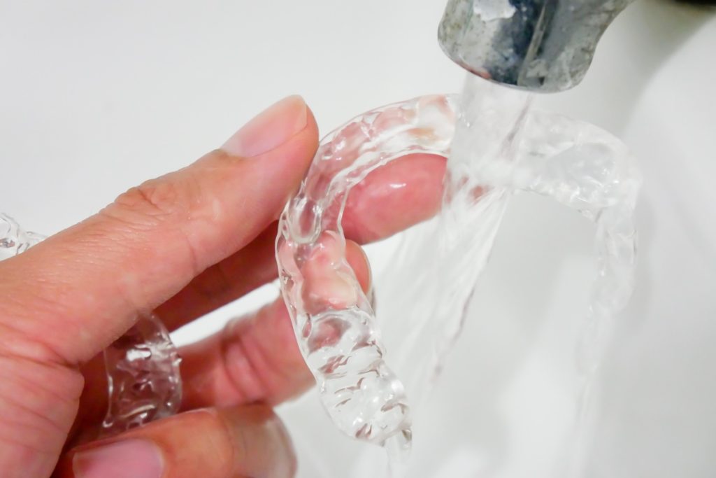 Patient rinsing off their clear aligners in the sink