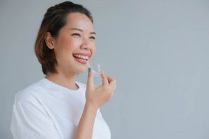 a patient smiling and holding their Invisalign aligner 