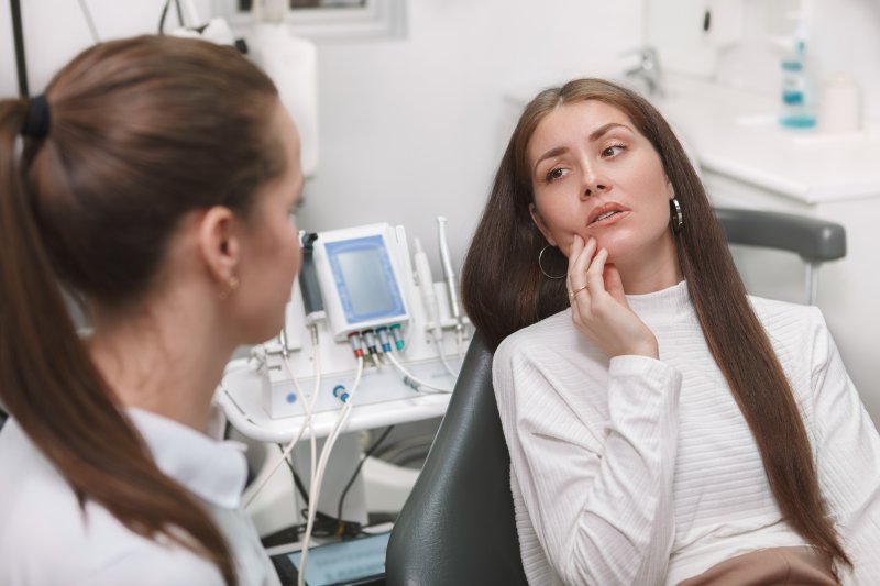 Patient holding her cheek due to orthodontic emergencies