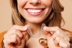 Woman holding Invisalign clear aligner. 