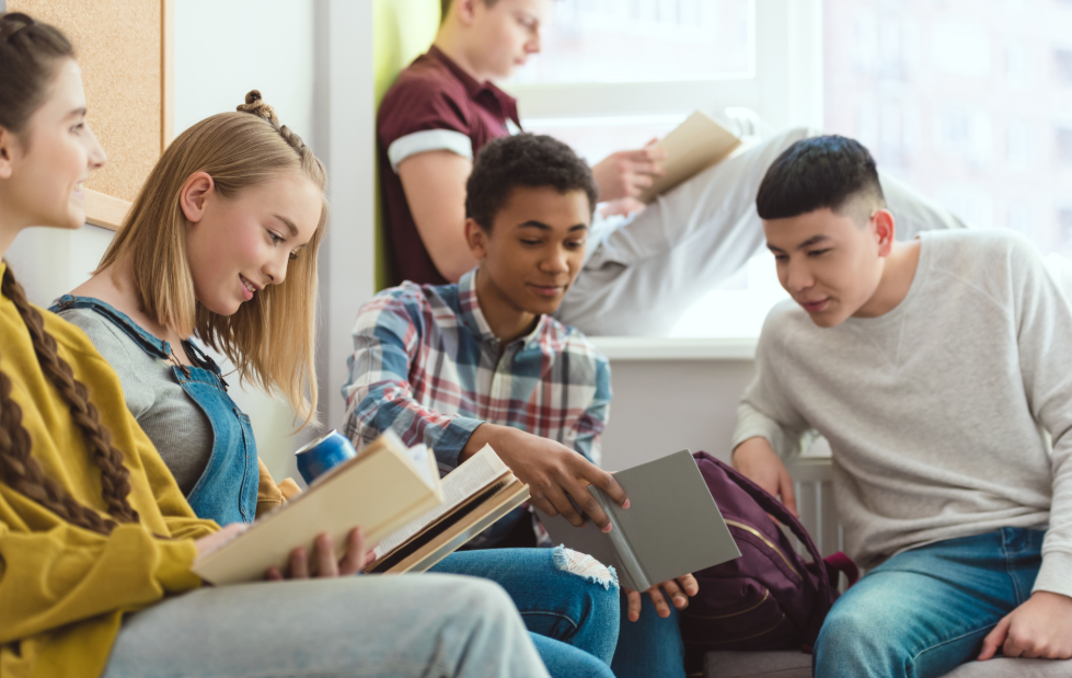 Group of teens with textbooks sitting in a circle at school