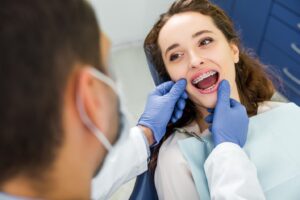Dentist examining adult woman smiling wearing braces.